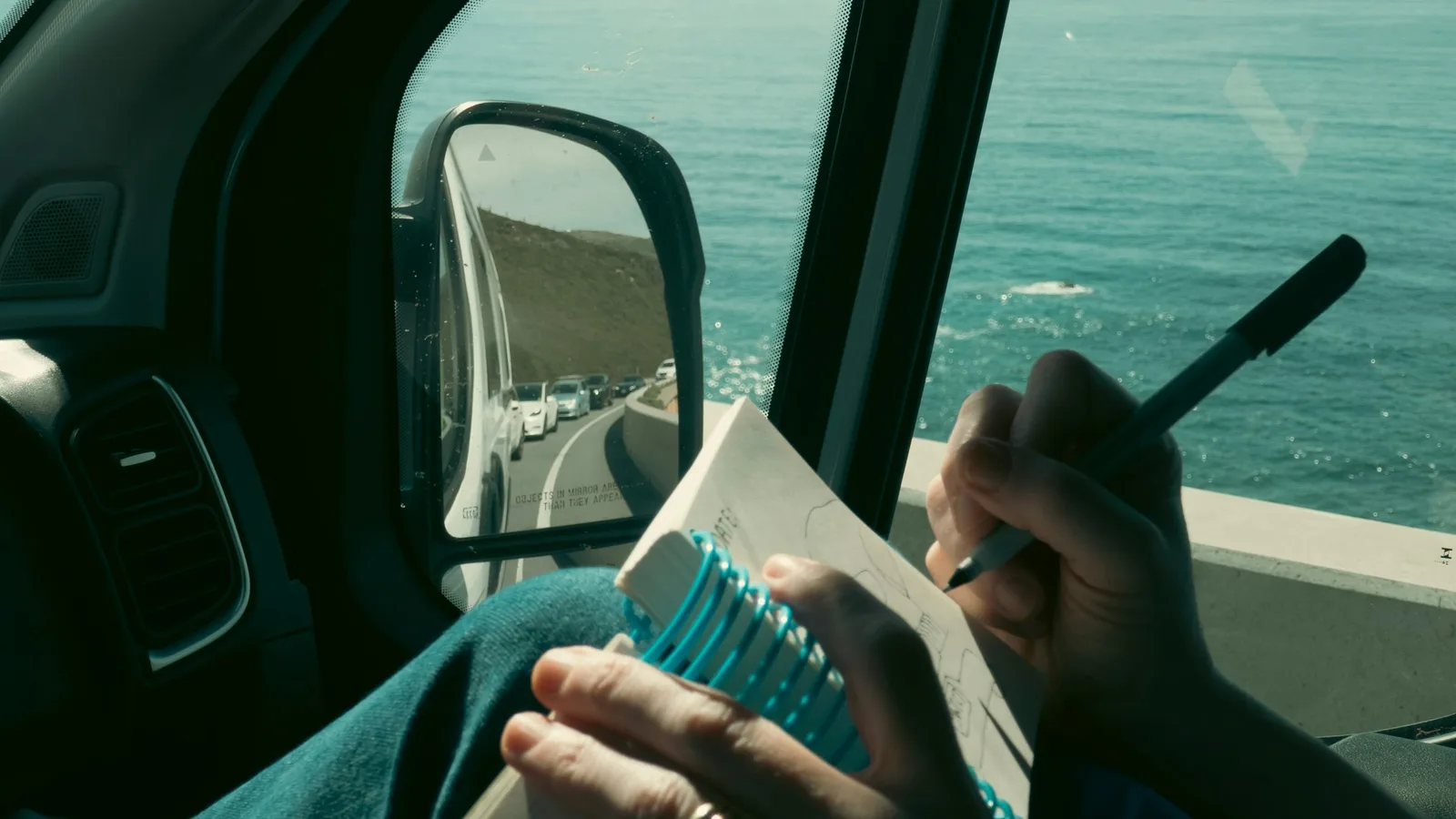 Driver writing a trip into a notebook in the car